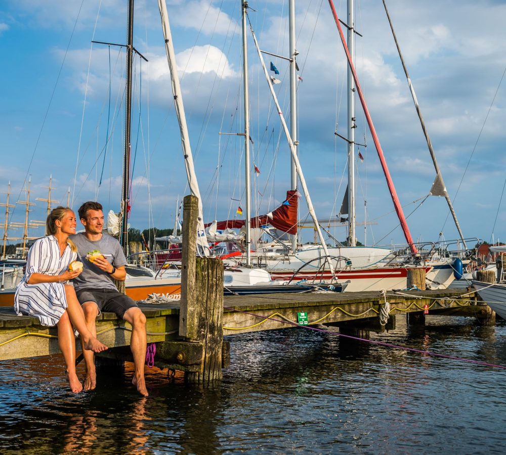 Paar isst Fischbrötchen auf Steg neben Boot (2)© LTM